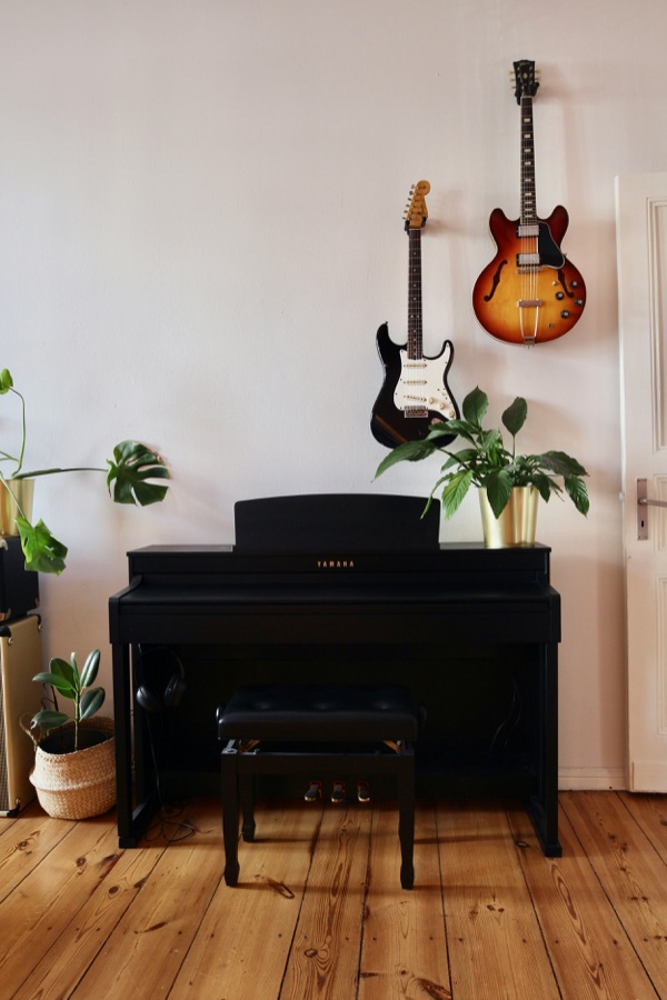 Klavier im Musikraum mit Gitarren an der Wand